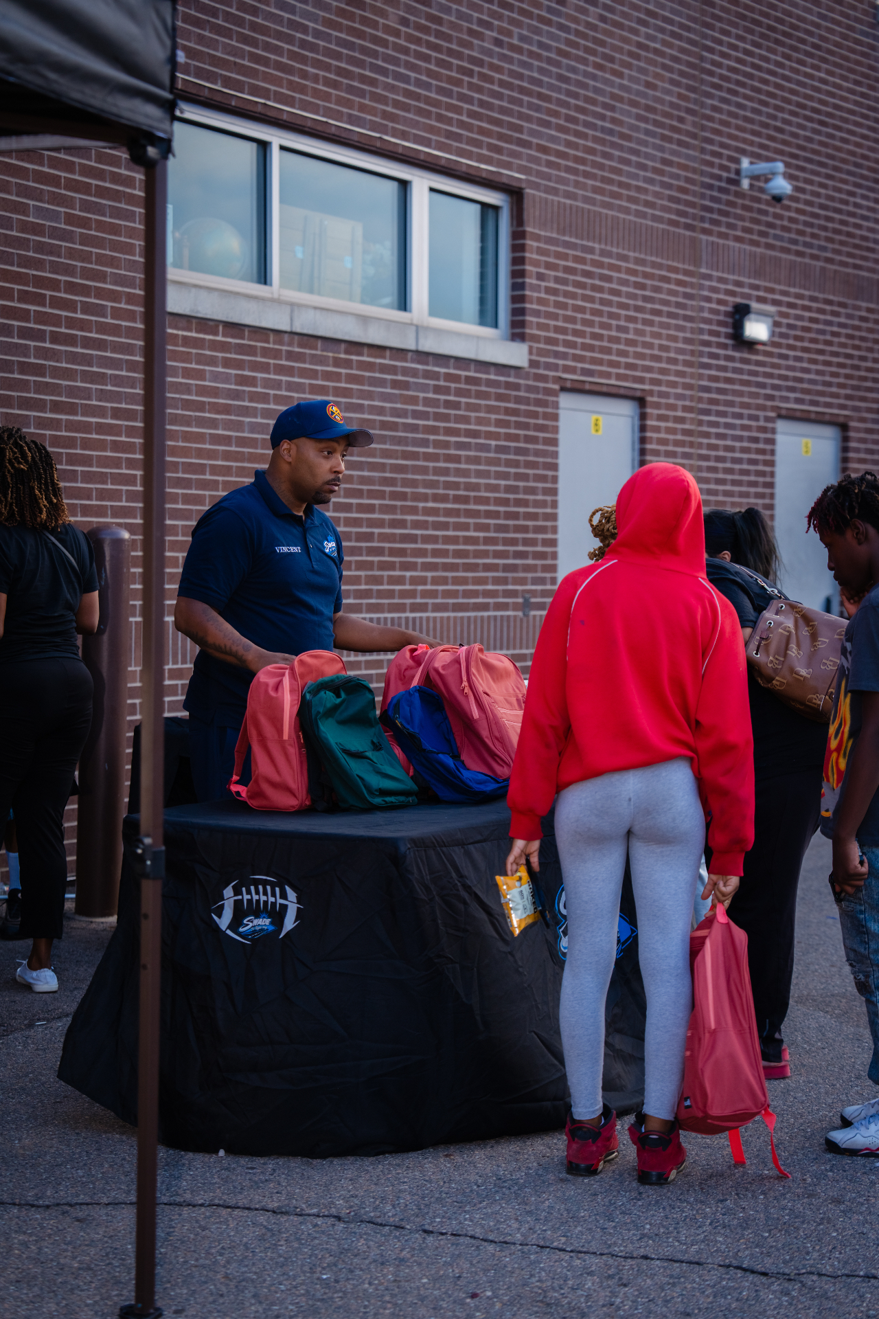 Volunteer handing out backpacks to students